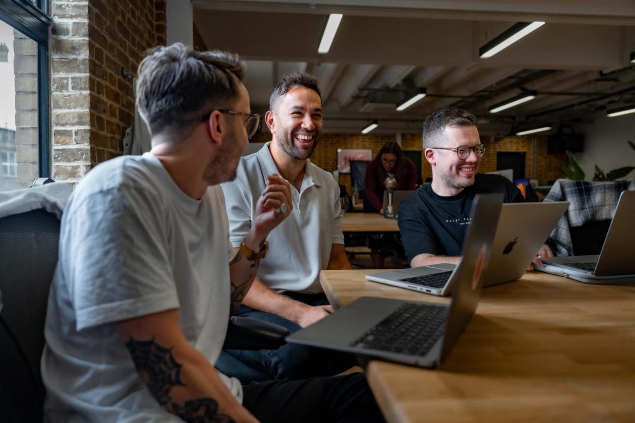 3 guys on laptops smiling